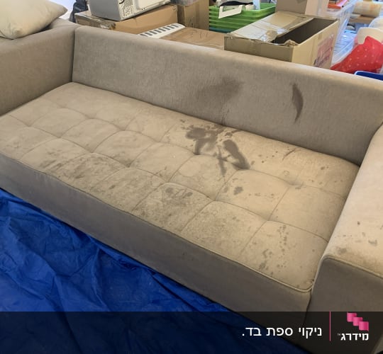ספה עם כתמים על בד, מונחת על יריעת פלסטיק כחולה